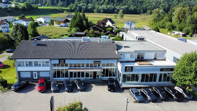 Luftbild des Autohauses mit beiden Gebäudeteilen, aufgereihten Fahrzeugen und der Wortmarke Schmid an der Fassade